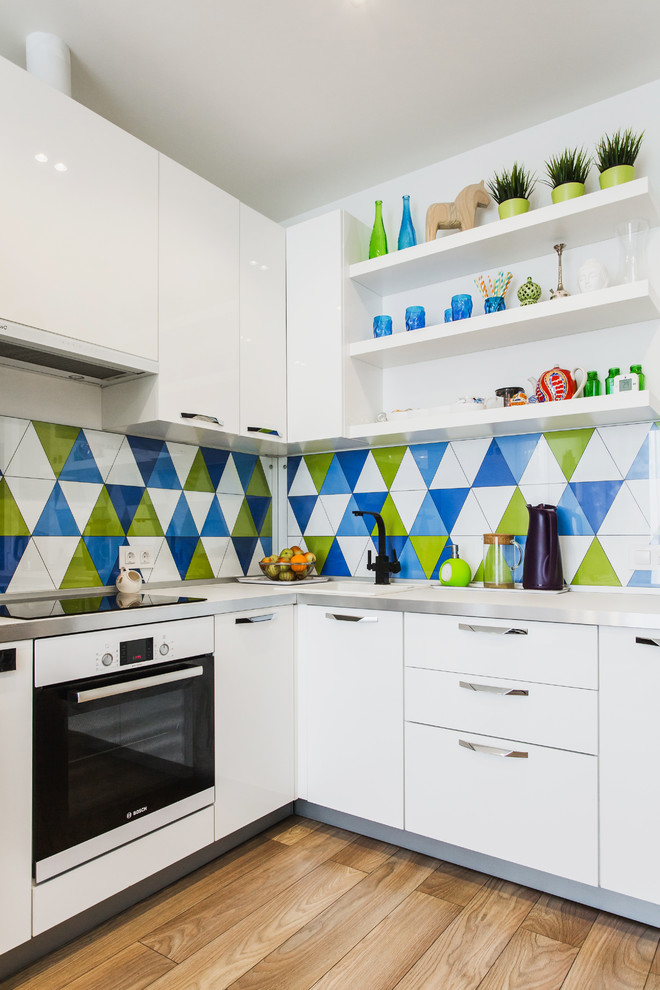 Photo of a small contemporary l-shaped kitchen in Moscow with flat-panel cabinets, white cabinets, solid surface benchtops, multi-coloured splashback, ceramic splashback, white appliances, light hardwood floors, no island and a drop-in sink.