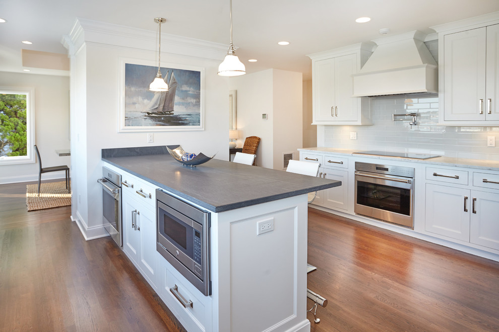 Photo of a large beach style u-shaped eat-in kitchen in New York with recessed-panel cabinets, white cabinets, laminate benchtops and with island.