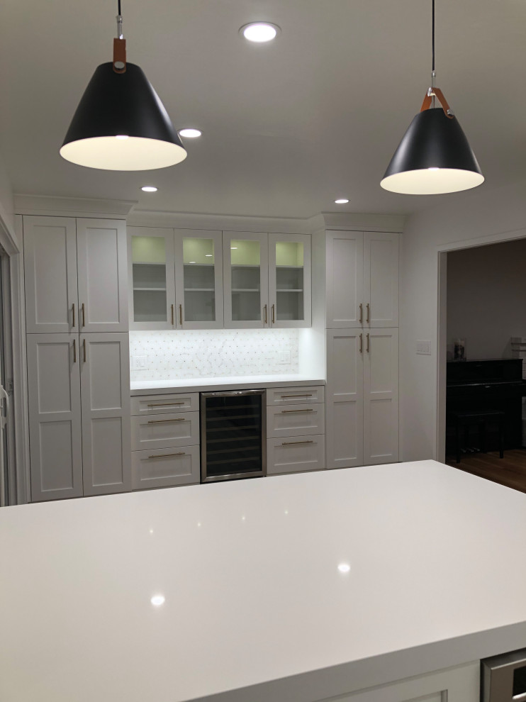 Inspiration for a mid-sized transitional l-shaped medium tone wood floor and brown floor eat-in kitchen remodel in San Francisco with a farmhouse sink, recessed-panel cabinets, white cabinets, quartz countertops, white backsplash, mosaic tile backsplash, stainless steel appliances, a peninsula and white countertops