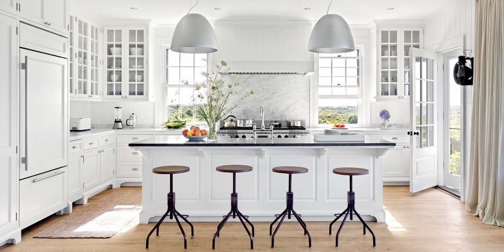 Inspiration for a mid-sized transitional l-shaped separate kitchen in Chicago with a farmhouse sink, shaker cabinets, white cabinets, white splashback, stainless steel appliances, light hardwood floors, with island, black floor, marble benchtops and marble splashback.