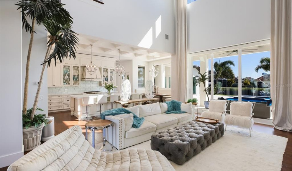 Photo of an expansive contemporary open concept family room in Tampa with a home bar, white walls, light hardwood floors, a standard fireplace, a concealed tv and vaulted.