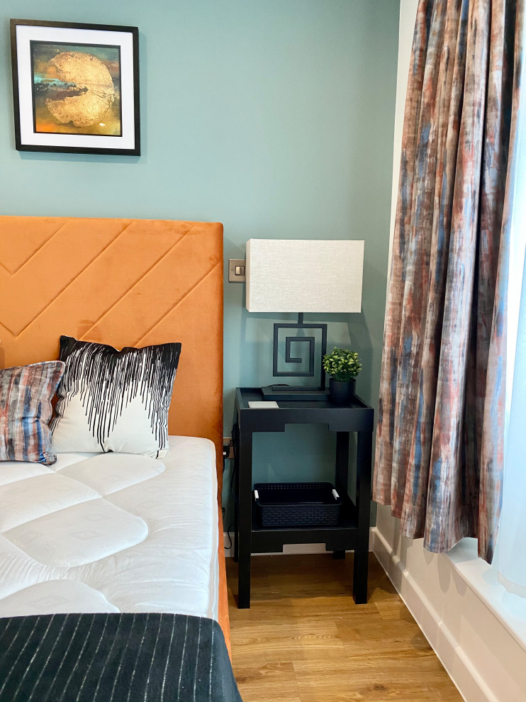 Foto de dormitorio principal actual pequeño con paredes azules, suelo laminado y suelo naranja