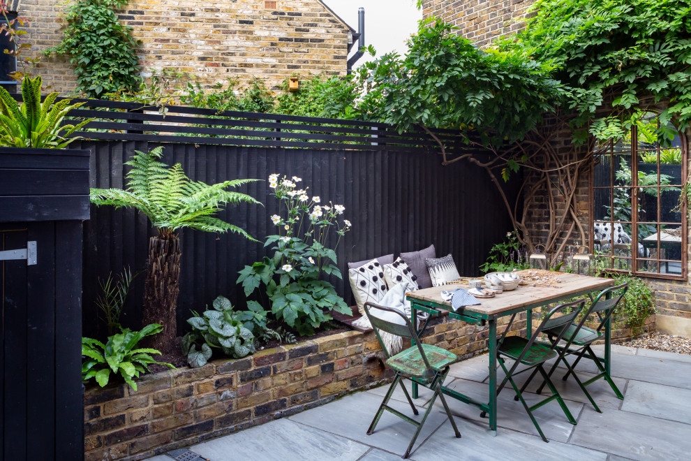 Kleiner, Halbschattiger Klassischer Garten hinter dem Haus, im Sommer mit Hochbeet, Natursteinplatten und Holzzaun in London