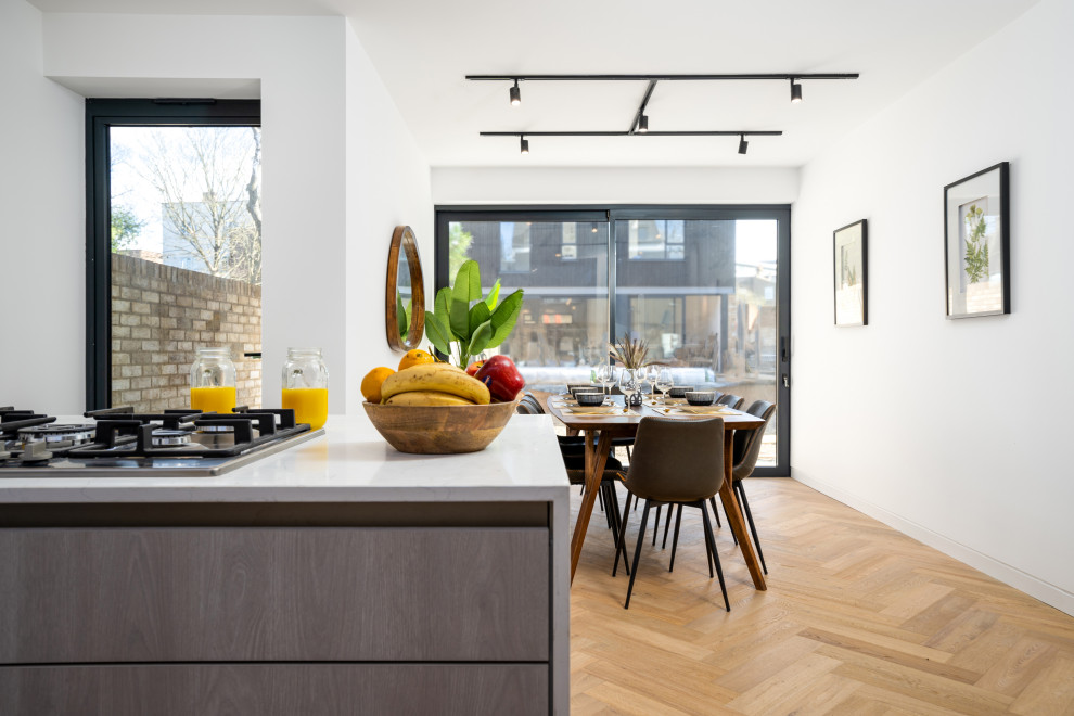 Idée de décoration pour une grande salle à manger ouverte sur la cuisine minimaliste avec un sol en bois brun et un sol marron.