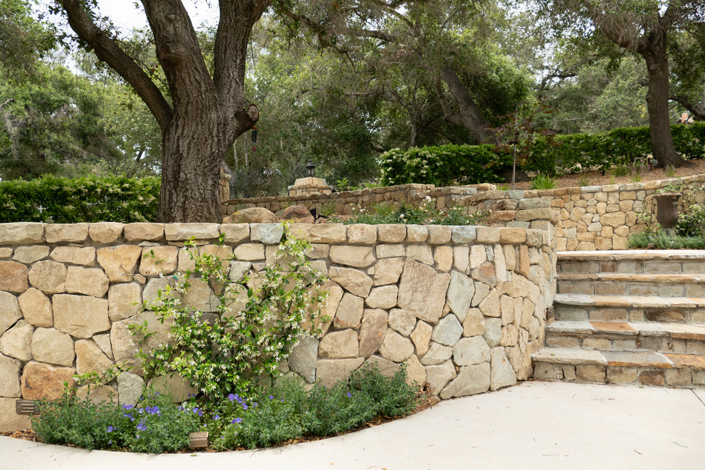 Arts and crafts courtyard partial sun formal garden in Los Angeles with a retaining wall and natural stone pavers.