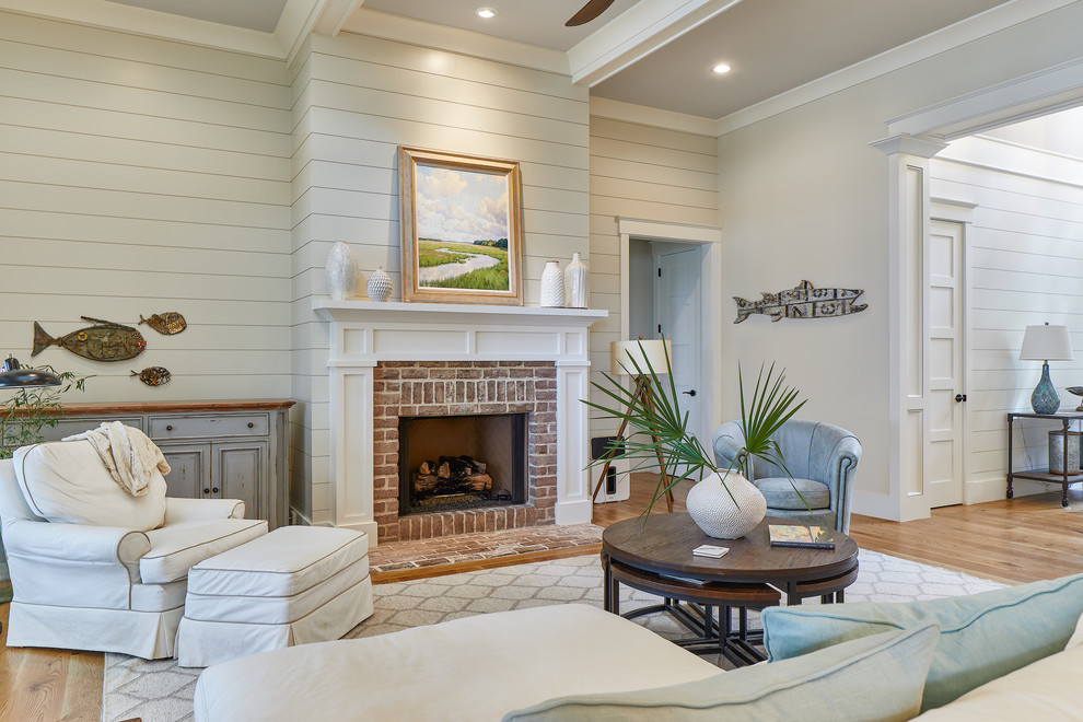 Inspiration for a large beach style open concept living room in Charleston with grey walls, light hardwood floors, a standard fireplace, a brick fireplace surround, no tv and brown floor.
