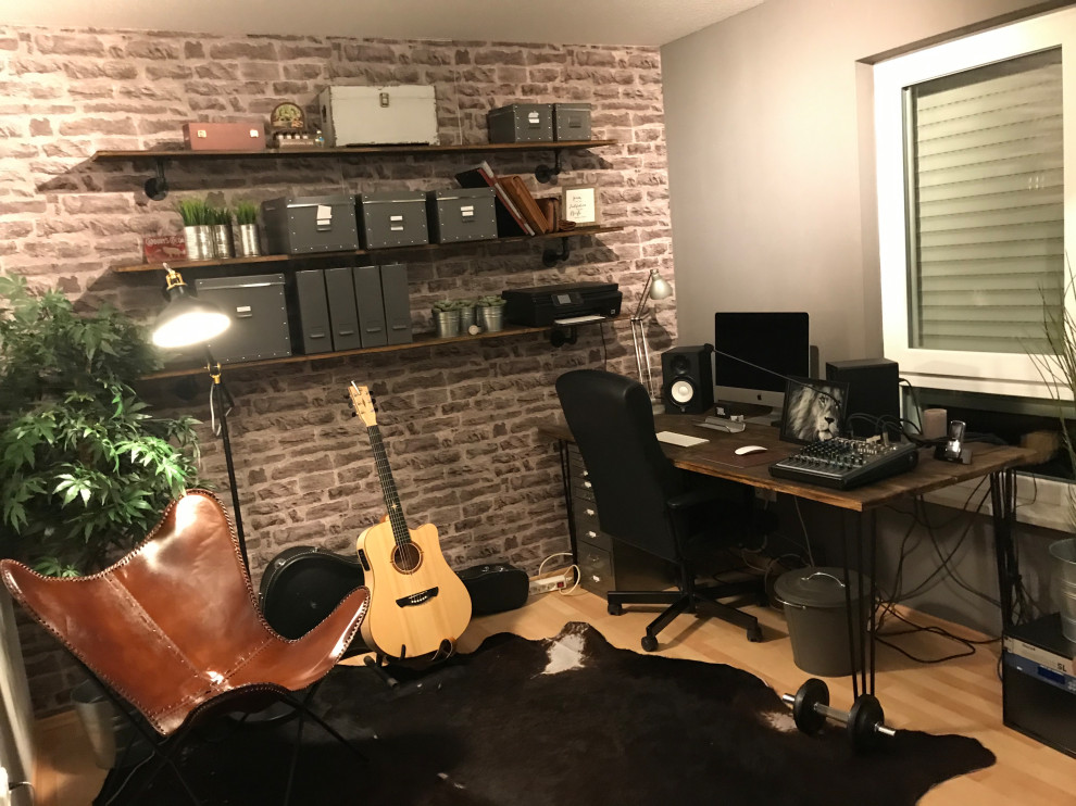 Bild på ett litet industriellt hemmastudio, med bruna väggar, laminatgolv, ett fristående skrivbord och brunt golv