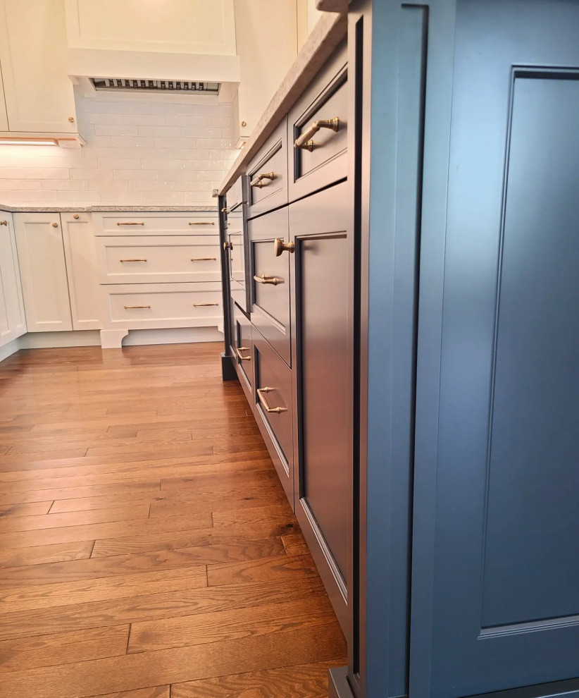 Example of a large transitional l-shaped medium tone wood floor and brown floor eat-in kitchen design in Boston with an undermount sink, shaker cabinets, blue cabinets, quartz countertops, white backsplash, subway tile backsplash, stainless steel appliances, an island and white countertops