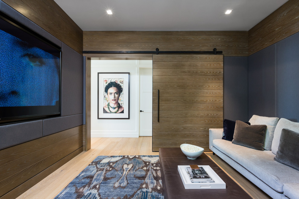 Inspiration for a contemporary enclosed home theatre in Vancouver with brown walls, light hardwood floors, a wall-mounted tv and beige floor.