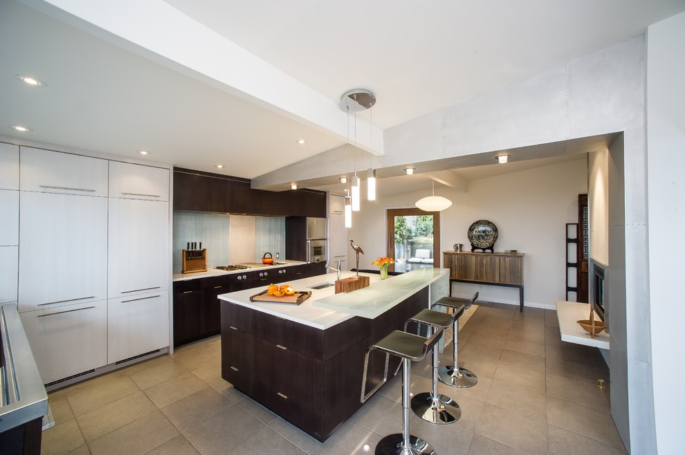 Large trendy l-shaped porcelain tile and beige floor enclosed kitchen photo in Seattle with an undermount sink, flat-panel cabinets, dark wood cabinets, quartzite countertops, white backsplash, glass tile backsplash, stainless steel appliances and an island