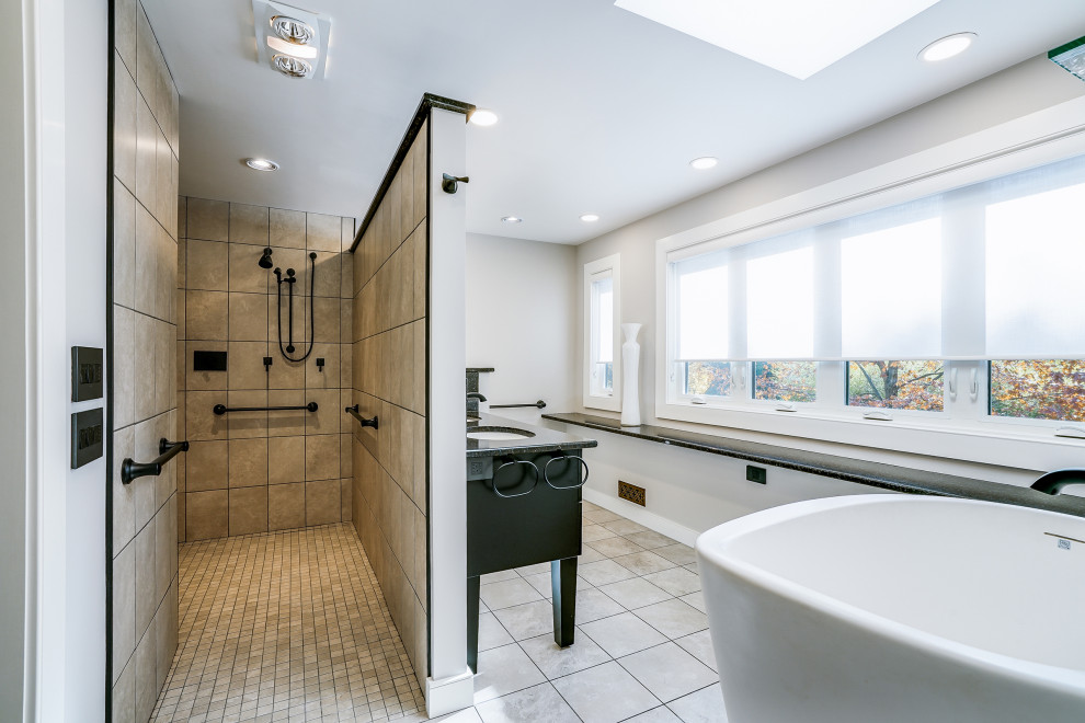 Large traditional bathroom in Philadelphia with flat-panel cabinets, dark wood cabinets, a freestanding bath, a built-in shower, beige tiles, white walls, a submerged sink, beige floors, an open shower, black worktops, a wall niche, double sinks and a freestanding vanity unit.