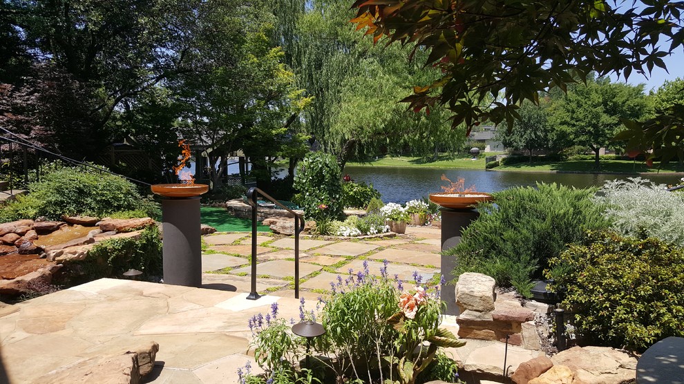 Photo of a tropical garden in Dallas with a fire feature and natural stone pavers.