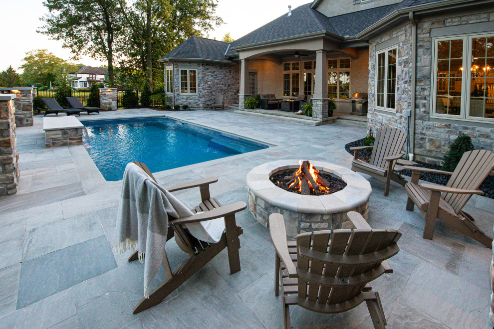 Immagine di una piscina monocorsia minimal rettangolare di medie dimensioni e dietro casa con fontane e pavimentazioni in pietra naturale
