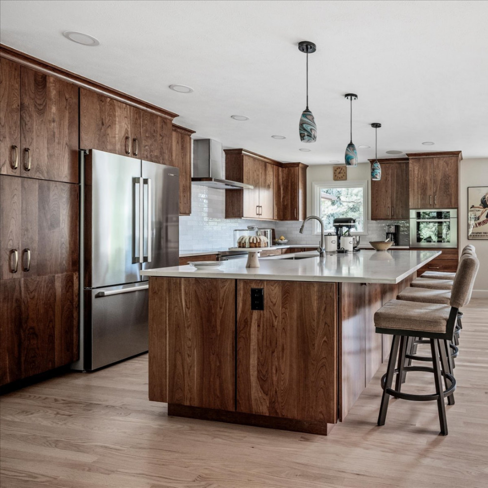 Eat-in kitchen - large transitional l-shaped light wood floor and brown floor eat-in kitchen idea in Denver with an undermount sink, flat-panel cabinets, medium tone wood cabinets, quartzite countertops, white backsplash, ceramic backsplash, stainless steel appliances, an island and white countertops