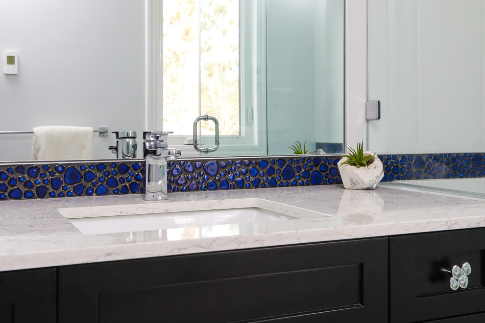 This is an example of a mid-sized transitional master bathroom in Toronto with recessed-panel cabinets, black cabinets, a corner shower, a two-piece toilet, blue tile, ceramic tile, porcelain floors, an undermount sink, engineered quartz benchtops, grey floor, a hinged shower door and white benchtops.