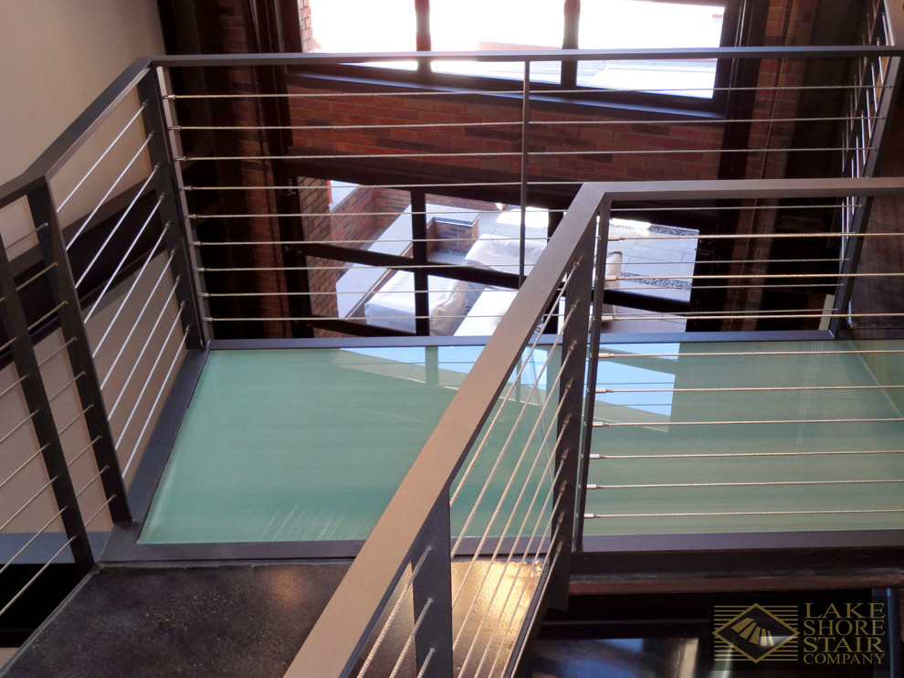 This is an example of an expansive modern wood l-shaped staircase in Chicago with metal risers and cable railing.