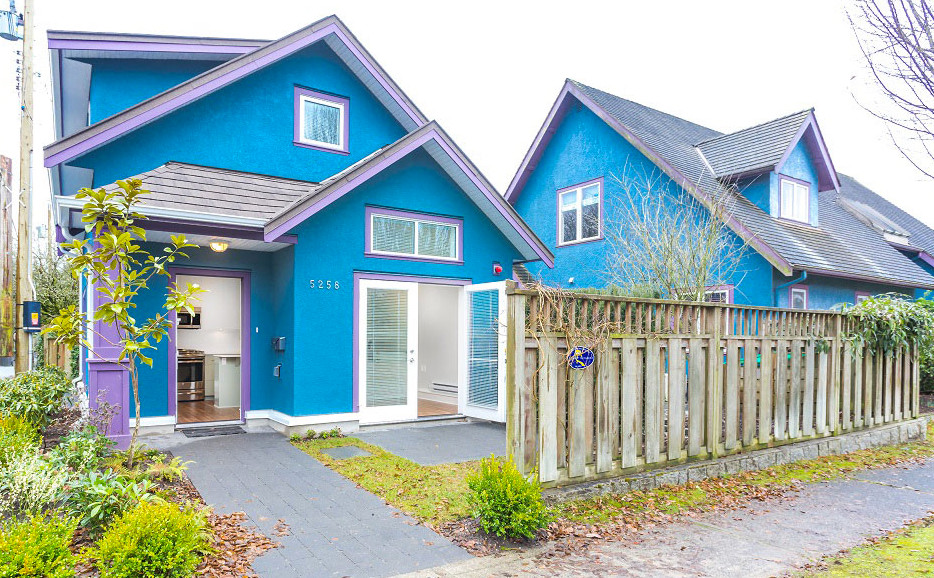 This is an example of a mid-sized eclectic one-storey stucco blue house exterior in Vancouver with a gable roof and a shingle roof.