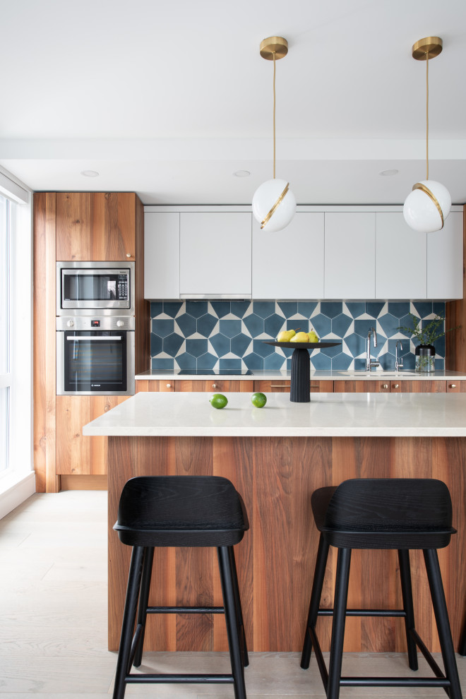 Mid-sized modern galley eat-in kitchen in Vancouver with an undermount sink, flat-panel cabinets, medium wood cabinets, quartzite benchtops, blue splashback, medium hardwood floors, with island and beige benchtop.