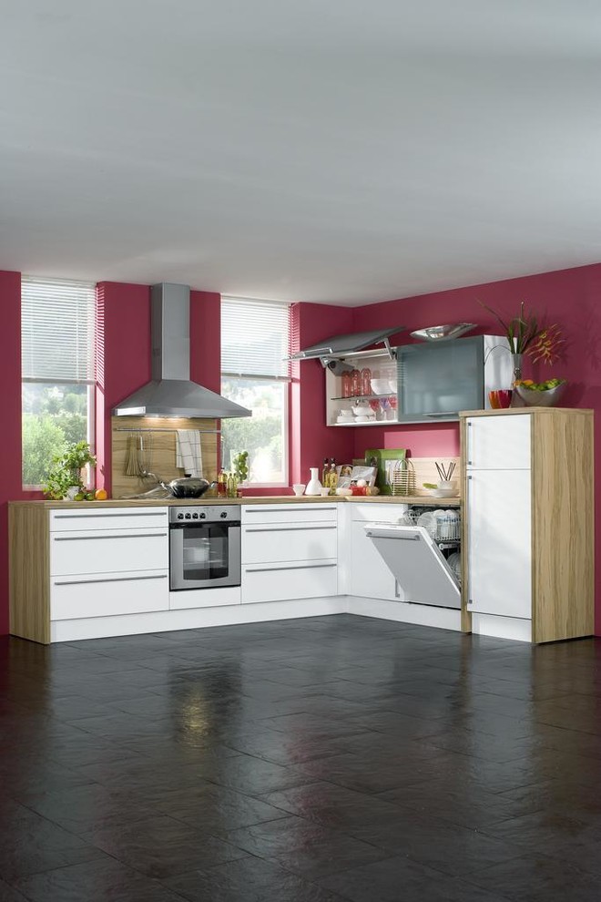 Inredning av ett modernt litet kök, med en nedsänkt diskho, släta luckor, vita skåp, träbänkskiva, rostfria vitvaror och brunt golv