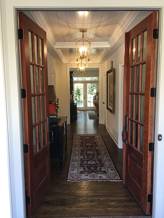 Пример оригинального дизайна: входная дверь среднего размера в стиле кантри с белыми стенами, темным паркетным полом, двустворчатой входной дверью, входной дверью из темного дерева, коричневым полом и кессонным потолком