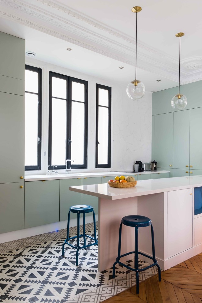Inspiration for a contemporary u-shaped kitchen in Paris with flat-panel cabinets, green cabinets, white splashback, a peninsula, stone slab splashback, panelled appliances and multi-coloured floor.