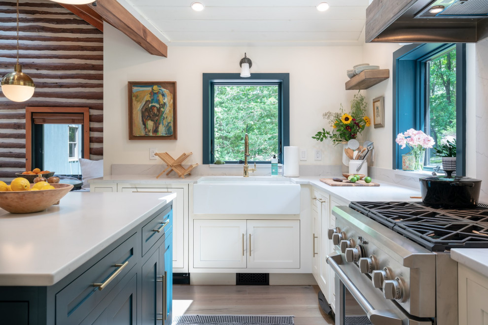 Inspiration for a transitional l-shaped kitchen in Phoenix with a farmhouse sink, shaker cabinets, white cabinets, stainless steel appliances, medium hardwood floors, with island, brown floor, white benchtop, exposed beam, timber and vaulted.