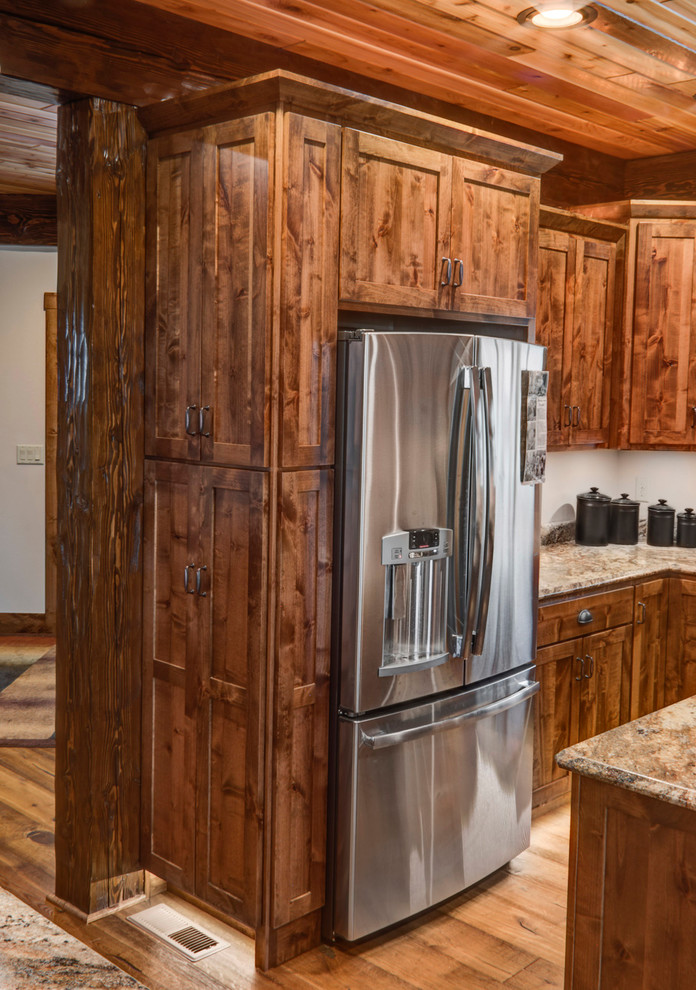 Example of a small mountain style galley medium tone wood floor eat-in kitchen design with an undermount sink, shaker cabinets, medium tone wood cabinets, laminate countertops, white backsplash, stainless steel appliances and two islands