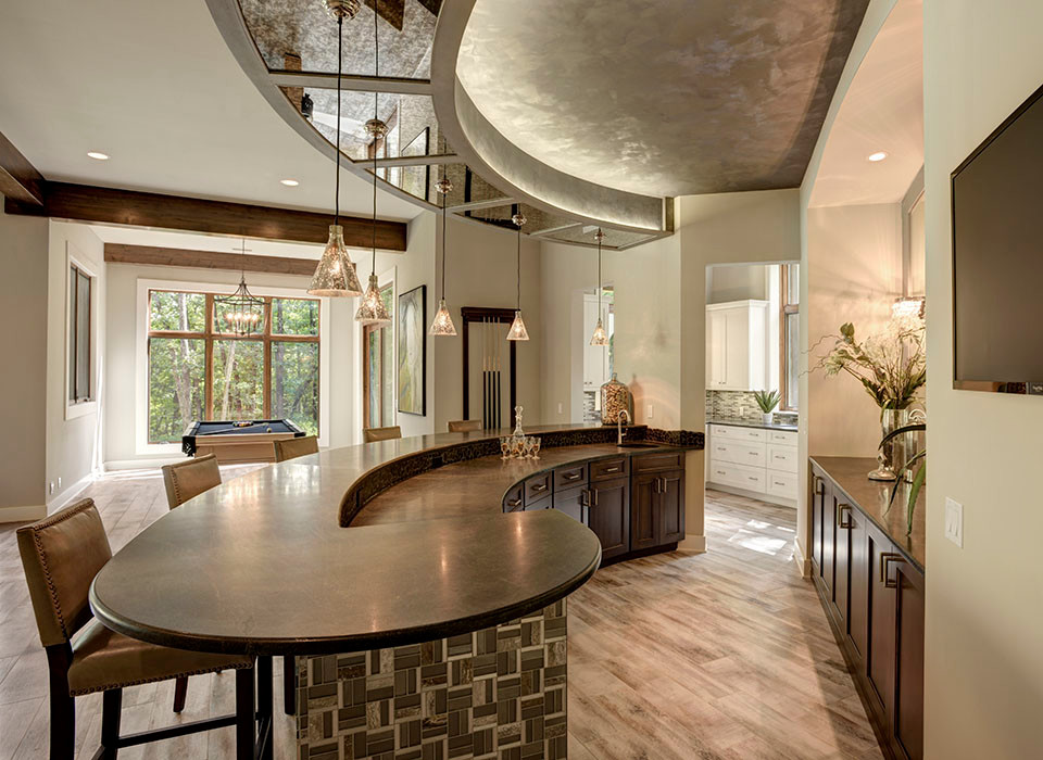 Inspiration for an expansive transitional galley seated home bar in Kansas City with an undermount sink, shaker cabinets, dark wood cabinets, granite benchtops, porcelain floors and grey floor.