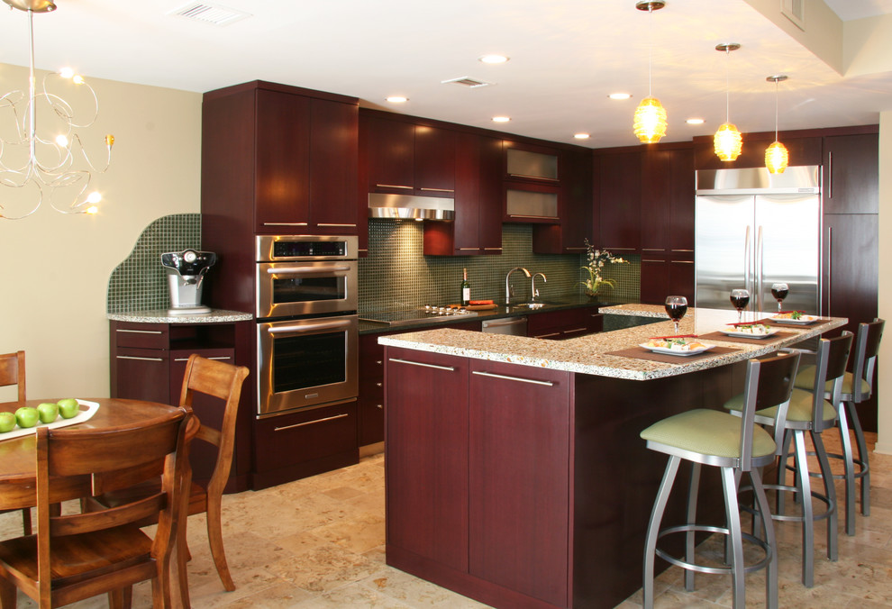 This is an example of a mid-sized contemporary l-shaped eat-in kitchen in Chicago with an undermount sink, flat-panel cabinets, dark wood cabinets, recycled glass benchtops, green splashback, glass tile splashback, stainless steel appliances, limestone floors and with island.