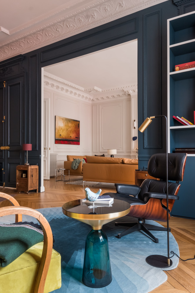 パリにあるミッドセンチュリースタイルのおしゃれな書斎 (青い壁、淡色無垢フローリング、標準型暖炉、石材の暖炉まわり、自立型机、ベージュの床) の写真
