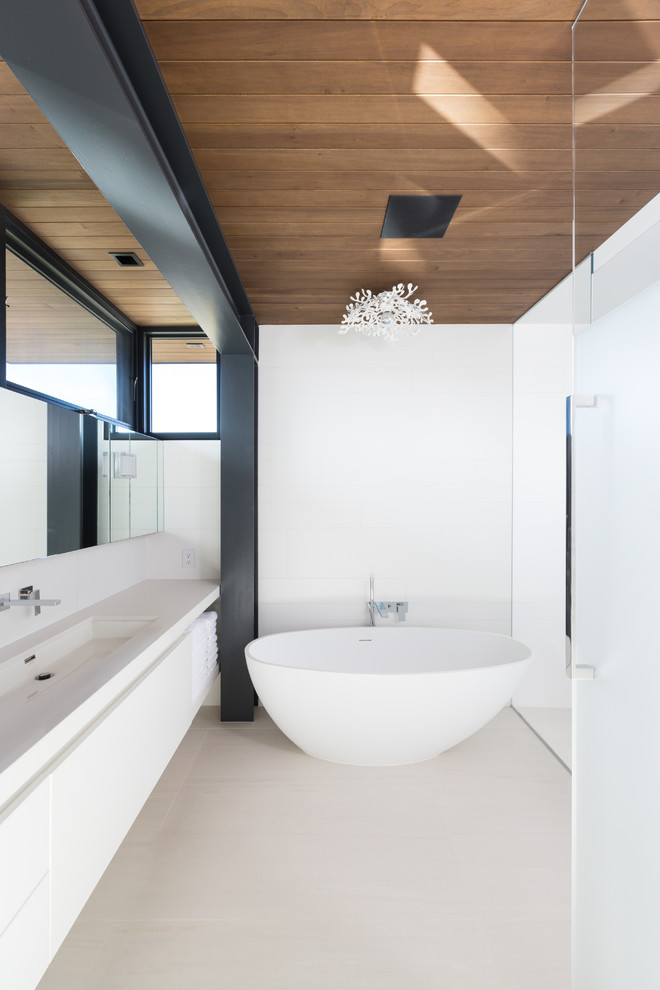 Inspiration for a large master bathroom in Vancouver with flat-panel cabinets, white cabinets, a freestanding tub, a double shower, white tile, porcelain tile, white walls, porcelain floors, a trough sink and quartzite benchtops.
