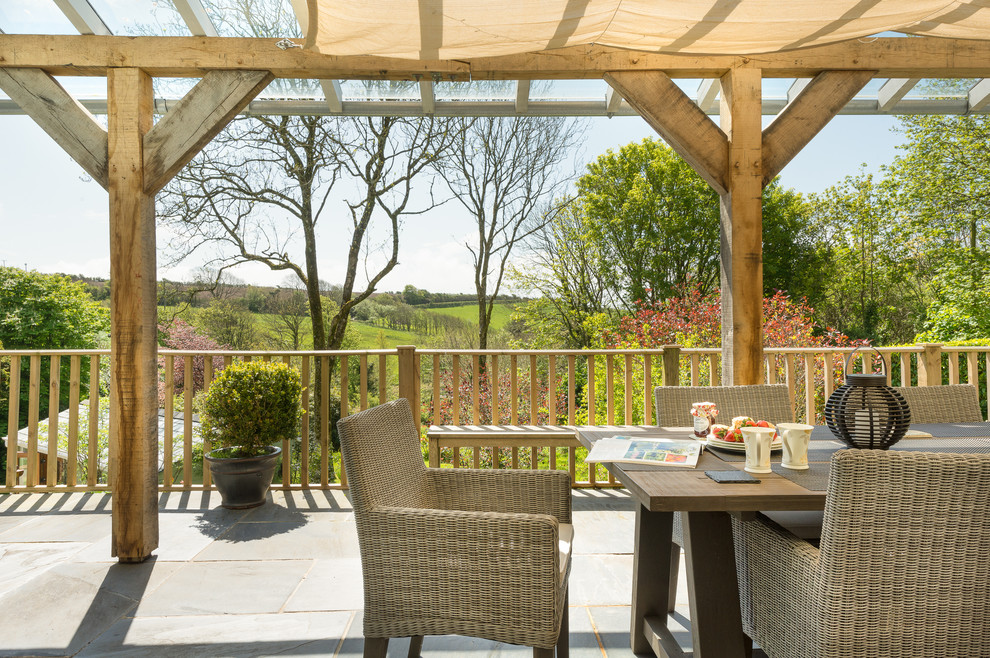 This is an example of a large country backyard deck in Devon with a pergola.