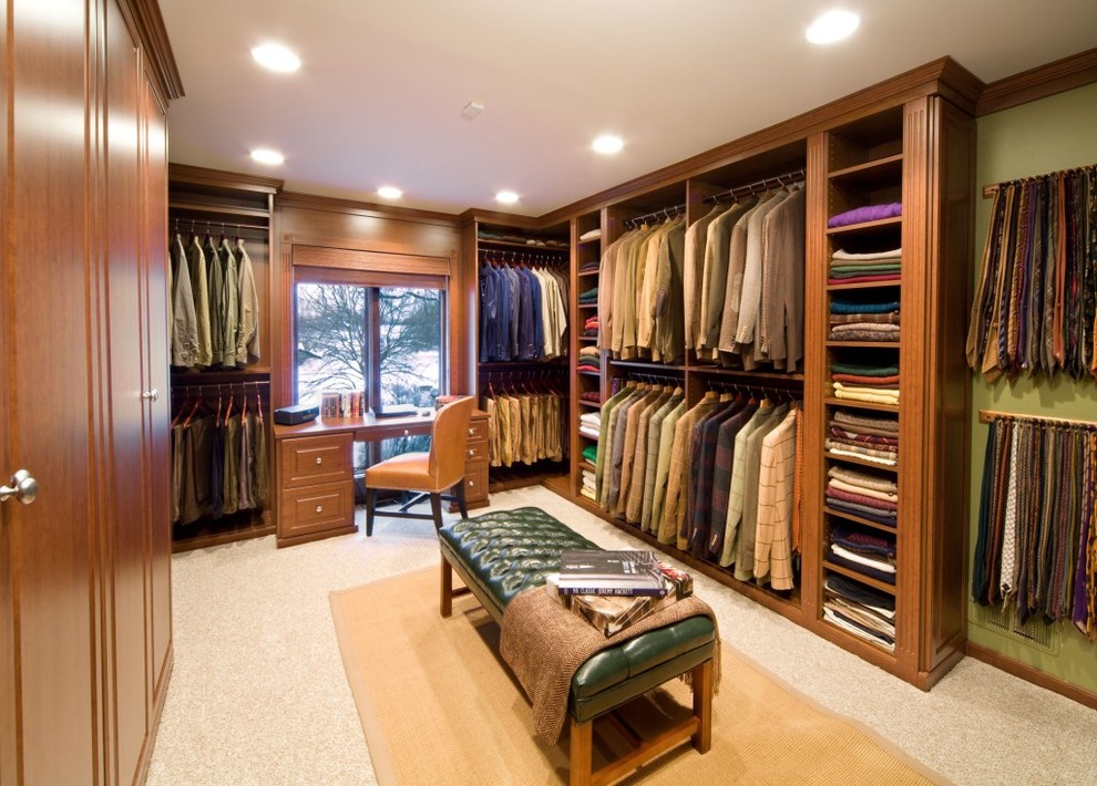 This is an example of an expansive traditional men's walk-in wardrobe in Chicago with raised-panel cabinets, medium wood cabinets and carpet.
