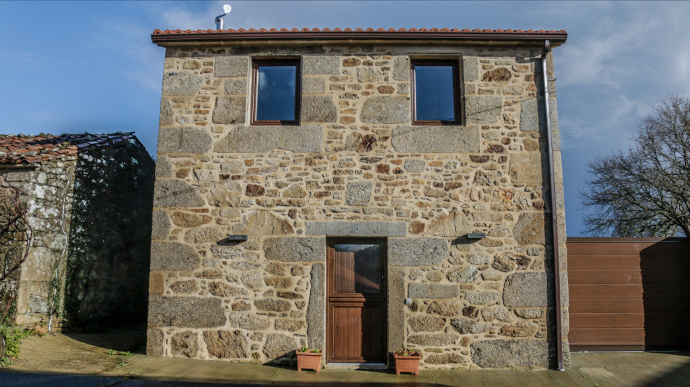 Cette image montre une grande façade de maison marron chalet en pierre et bardeaux à un étage avec un toit à deux pans et un toit en tuile.