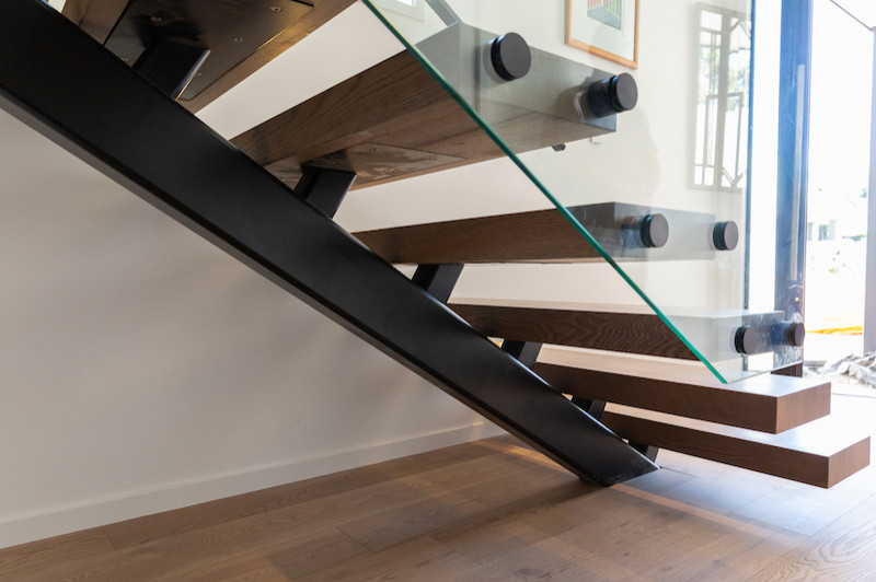Photo of a mid-sized modern wood floating staircase in Auckland with open risers and metal railing.