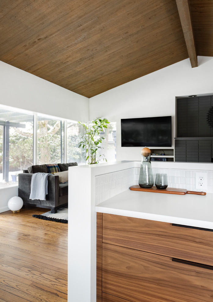 This is an example of a small midcentury u-shaped eat-in kitchen in Portland with an undermount sink, flat-panel cabinets, dark wood cabinets, quartz benchtops, white splashback, ceramic splashback, panelled appliances, terrazzo floors, black floor and white benchtop.