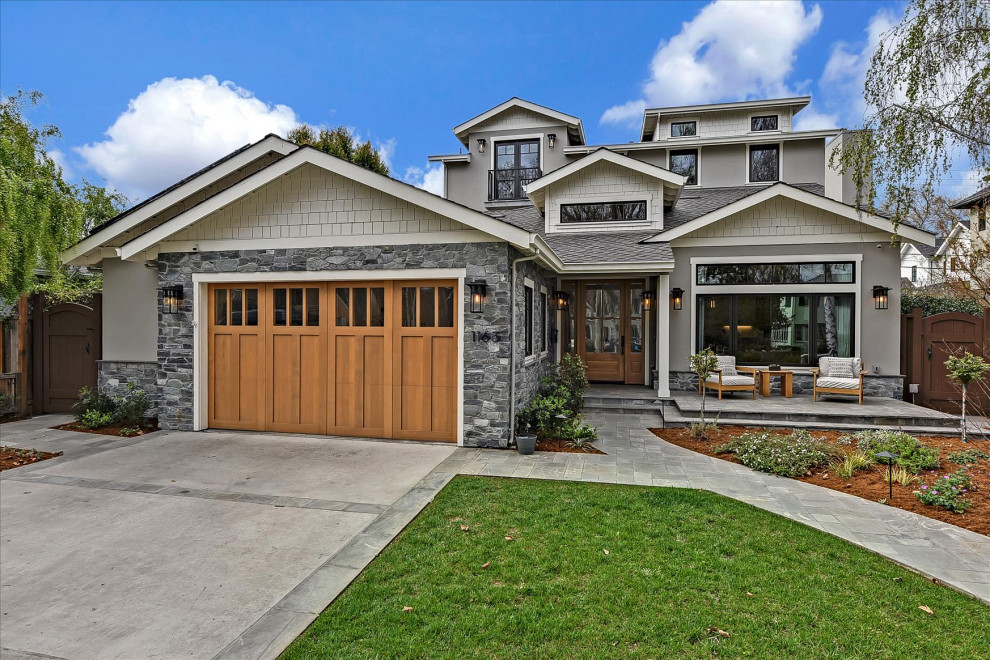 This is an example of a large arts and crafts split-level beige house exterior in San Francisco with stone veneer, a gable roof, a mixed roof, a grey roof and shingle siding.