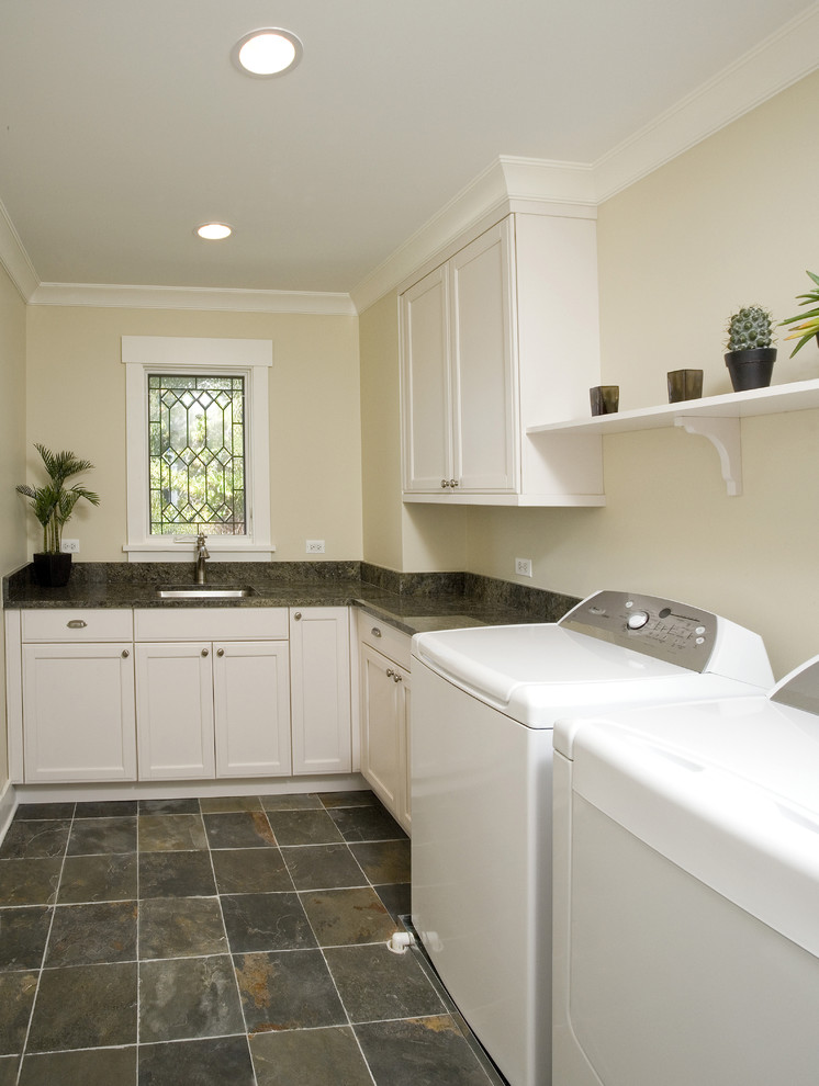 Photo of a large arts and crafts l-shaped dedicated laundry room in Chicago with an undermount sink, recessed-panel cabinets, white cabinets, granite benchtops, brown splashback, granite splashback, beige walls, slate floors, a side-by-side washer and dryer, multi-coloured floor and brown benchtop.