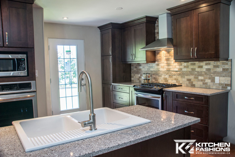 Example of a large transitional u-shaped medium tone wood floor open concept kitchen design with a farmhouse sink, shaker cabinets, dark wood cabinets, quartz countertops, brown backsplash, stone tile backsplash, stainless steel appliances and an island