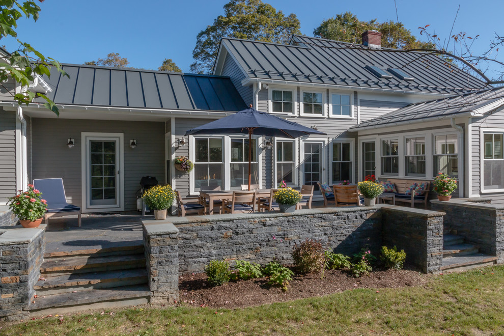 Large country two-storey grey house exterior in Boston with wood siding, a gable roof and a metal roof.