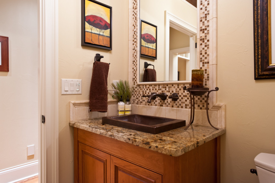 Traditional powder room in Milwaukee with a drop-in sink, raised-panel cabinets, medium wood cabinets, granite benchtops, a one-piece toilet, beige tile and mosaic tile.