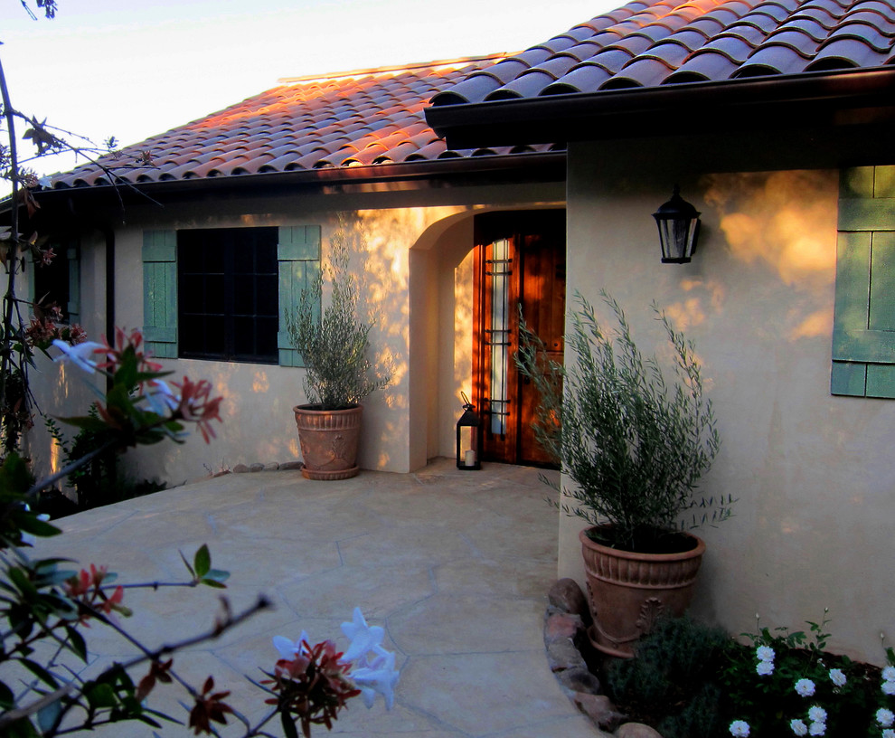 This is an example of a mid-sized mediterranean two-storey stucco beige house exterior in Santa Barbara with a gable roof and a tile roof.