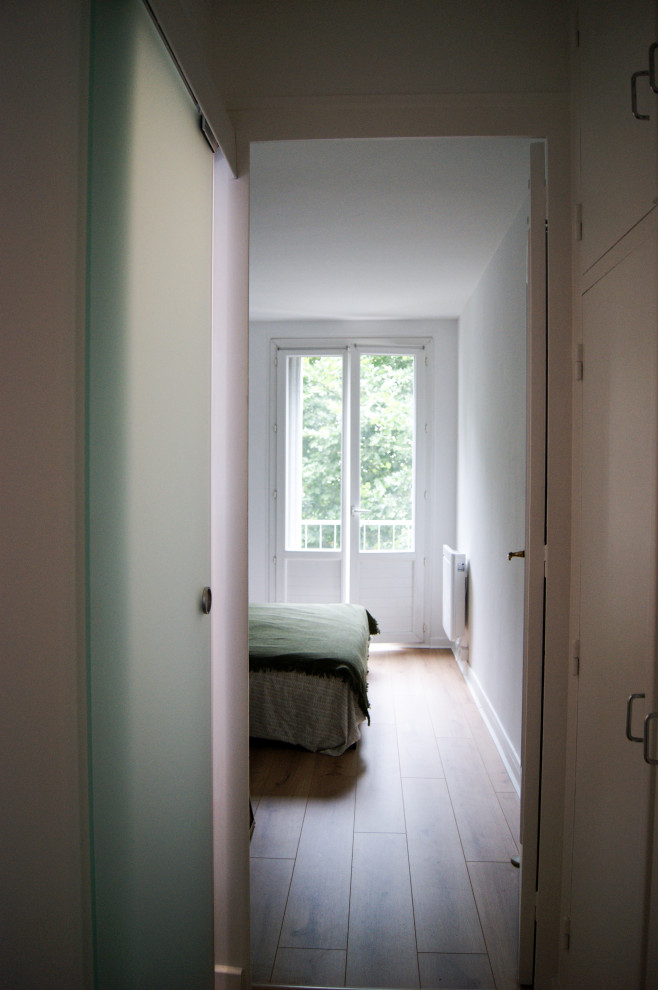 Idée de décoration pour un petit couloir minimaliste avec un mur blanc, parquet clair et un sol marron.