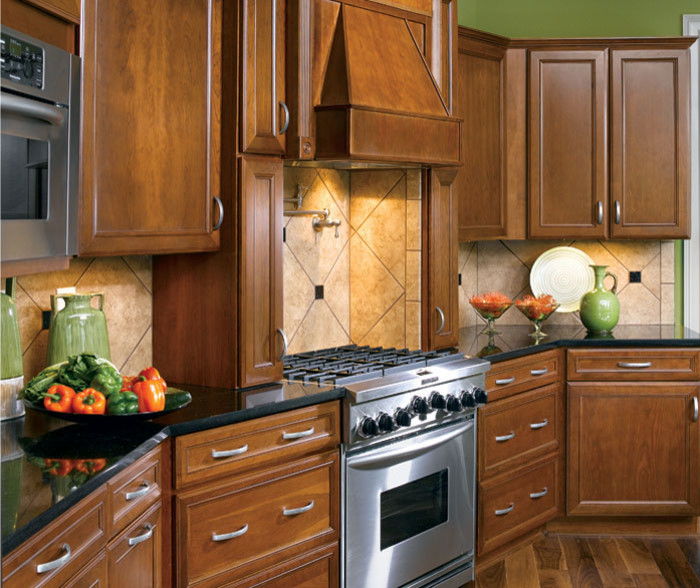 Mid-sized transitional l-shaped dark wood floor and brown floor eat-in kitchen photo with an undermount sink, recessed-panel cabinets, brown cabinets, granite countertops, beige backsplash, porcelain backsplash, stainless steel appliances, an island and black countertops