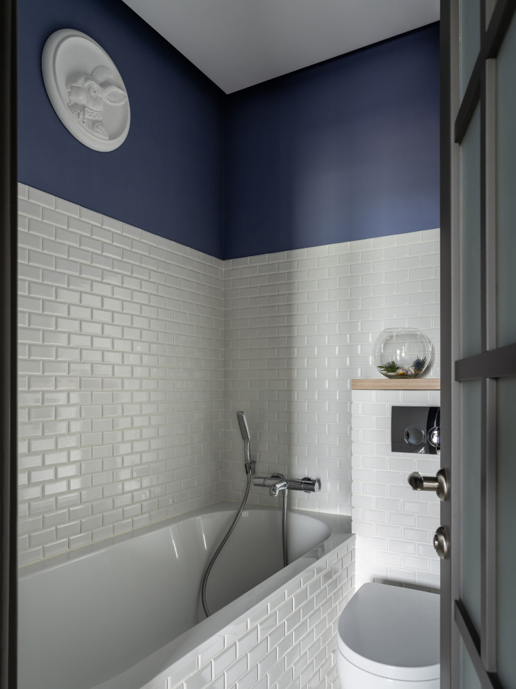 Cette photo montre une salle de bain principale chic avec une baignoire en alcôve, un combiné douche/baignoire, WC suspendus, un carrelage blanc, un carrelage métro et un mur bleu.