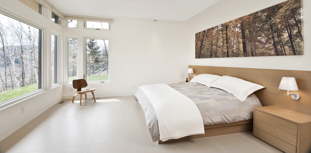 This is an example of a large contemporary master bedroom in Ottawa with white walls, porcelain floors, no fireplace and beige floor.