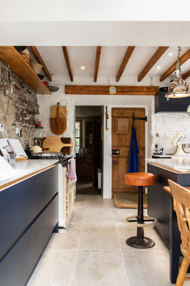 Design ideas for a mid-sized country u-shaped eat-in kitchen in Cornwall with flat-panel cabinets, blue cabinets, quartzite benchtops, coloured appliances, ceramic floors, with island, grey floor, white benchtop and exposed beam.