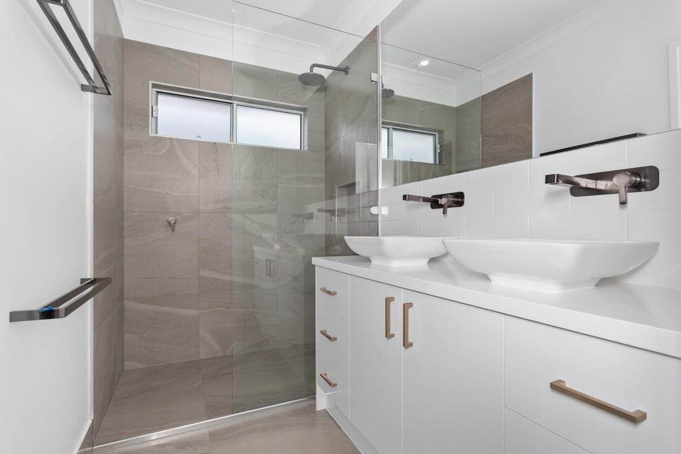 This is an example of a small contemporary master bathroom in Brisbane with white cabinets, an open shower, a one-piece toilet, white tile, ceramic tile, white walls, ceramic floors, a vessel sink, grey floor, an open shower and white benchtops.