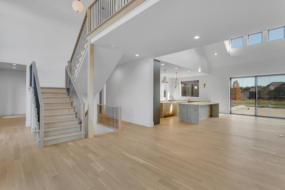 Inspiration for a huge transitional u-shaped light wood floor, beige floor and vaulted ceiling open concept kitchen remodel with an undermount sink, flat-panel cabinets, light wood cabinets, quartz countertops, white backsplash, stainless steel appliances, two islands and gray countertops
