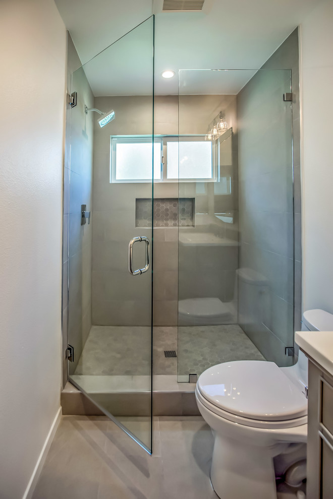 Photo of a small mediterranean 3/4 bathroom in Los Angeles with shaker cabinets, grey cabinets, an alcove shower, a one-piece toilet, gray tile, porcelain tile, grey walls, porcelain floors, a console sink, solid surface benchtops, grey floor and a hinged shower door.